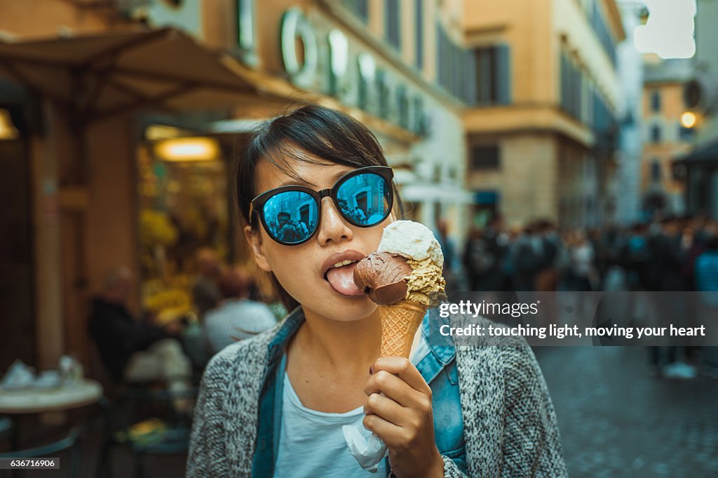 Young female tourist tasting Gelato / ice cream in Rome street