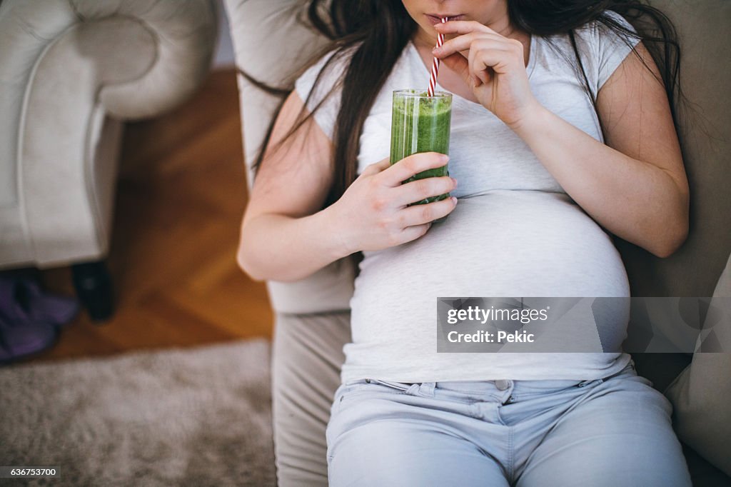 Pregnant woman drinking green smoothie