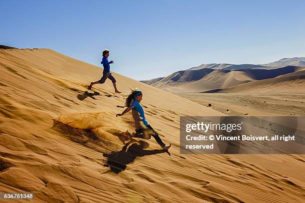two kids running down sossusvlei dunes - dead vlei namibia fotografías e imágenes de stock