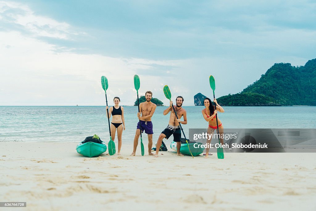 Four friends with puddles near kayaks on the beach