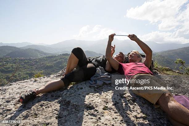 couple relax on rock ledge, using digital tablet - woman look straight black shirt stock pictures, royalty-free photos & images