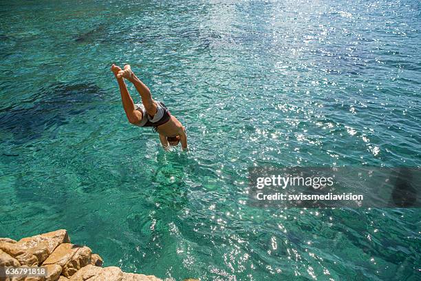 joven salta del acantilado al mar - lanzarse al agua fotografías e imágenes de stock