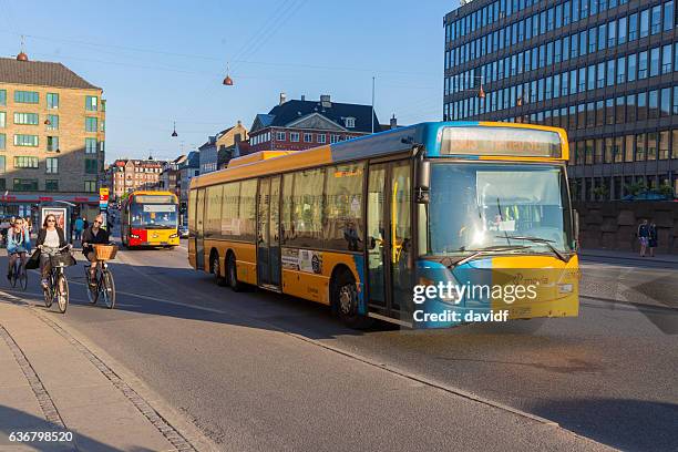 a public transport bus passes cyclists in copenhagen - bus denmark stock pictures, royalty-free photos & images