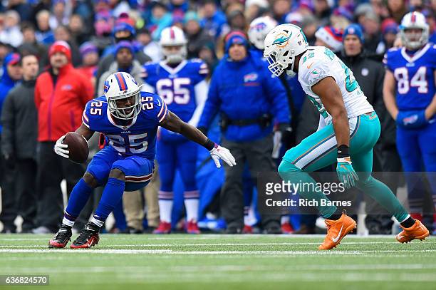 LeSean McCoy of the Buffalo Bills runs with the ball as Spencer Paysinger of the Miami Dolphins defends during the first quarter at New Era Field on...