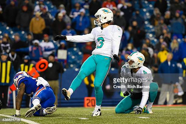 Andrew Franks of the Miami Dolphins watches the game winning field goal after kicking the ball from the hold of with teammate Matt Darr against the...