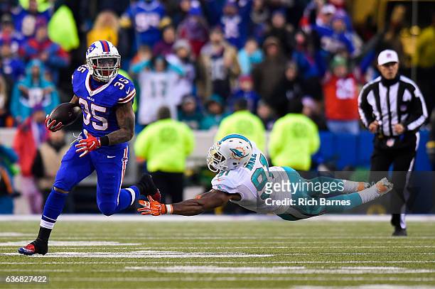 Mike Gillislee of the Buffalo Bills runs with the ball as Cameron Wake of the Miami Dolphins makes a diving tackle attempt during overtime at New Era...