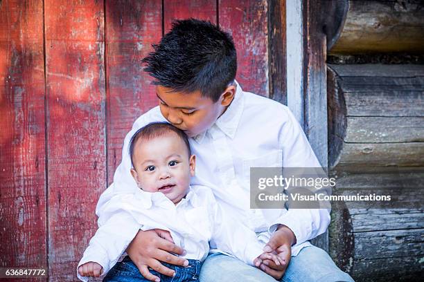 filipino boy holding kissing brother outside. - baby brother stock pictures, royalty-free photos & images