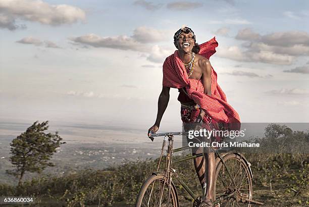 maasai warrior smiling on bike. kenya, africa. - masai mara national reserve stock pictures, royalty-free photos & images