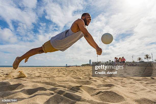 aktiver junger mann springt beim beachvolleyball - strandvolleyball spielerin stock-fotos und bilder