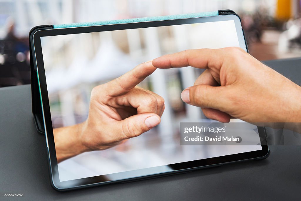 Fingers touching over a tablet computer.