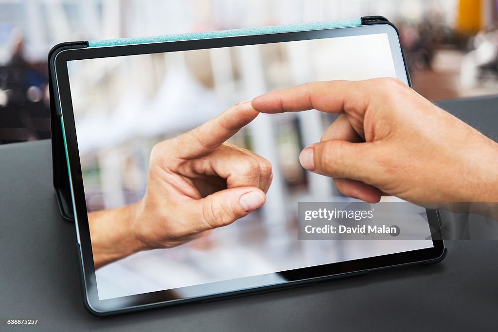 Fingers touching  over a tablet computer.