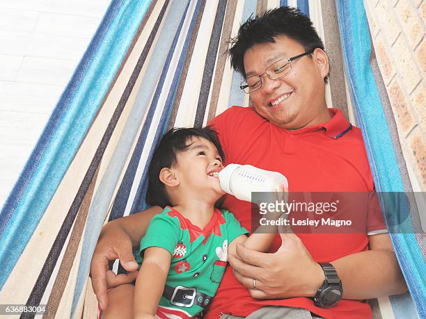 summer christmas - toddler and dad in the hammock - philippines family celebration stock pictures, royalty-free photos & images
