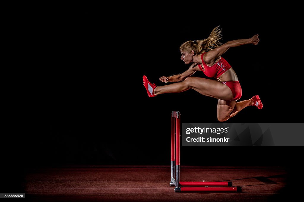 Athlete clearing hurdle