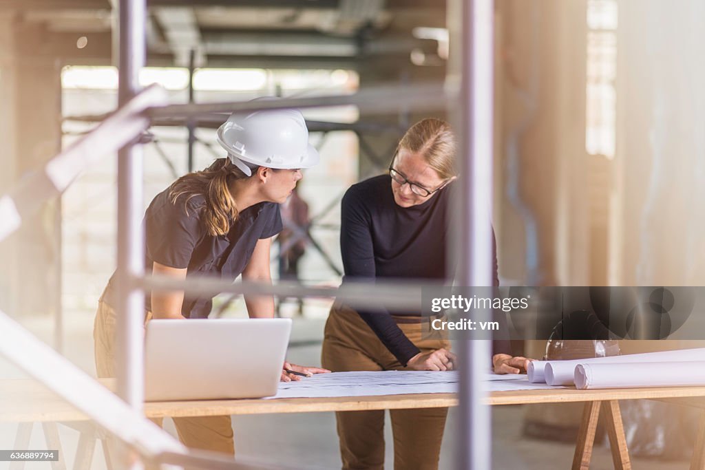Two female architects reviewing blueprints