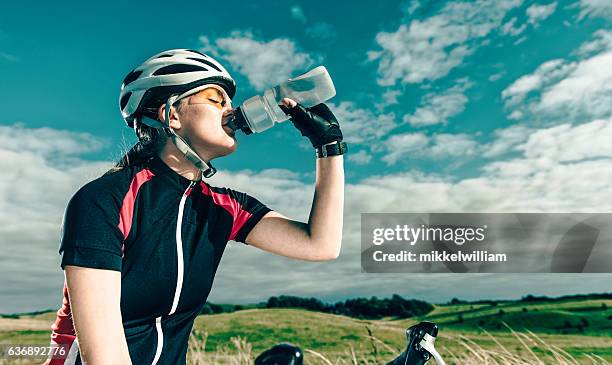 プロの女性の自転車ライダーは休憩中に水を飲みます - ロードバイク ストックフォトと画像