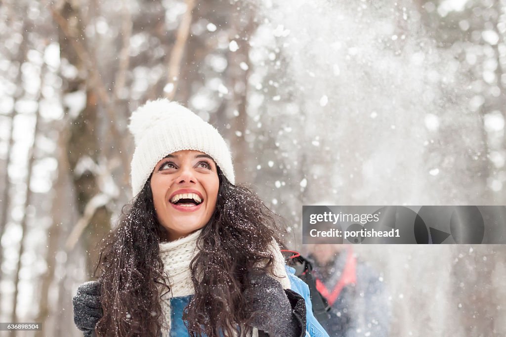Cheerful young woman having fun in the snow forest