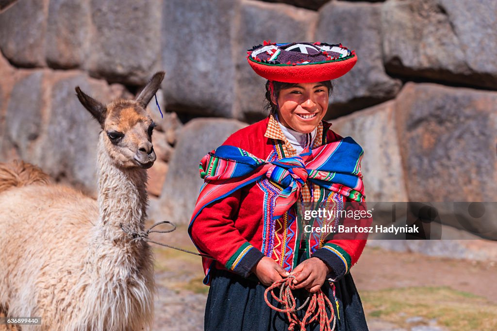 Peruvian girl wearing national clothing walking with llama near Cuzco