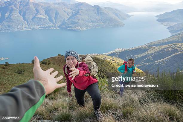hiker giving helping hand to teammate - team climbing up to mountain top stockfoto's en -beelden