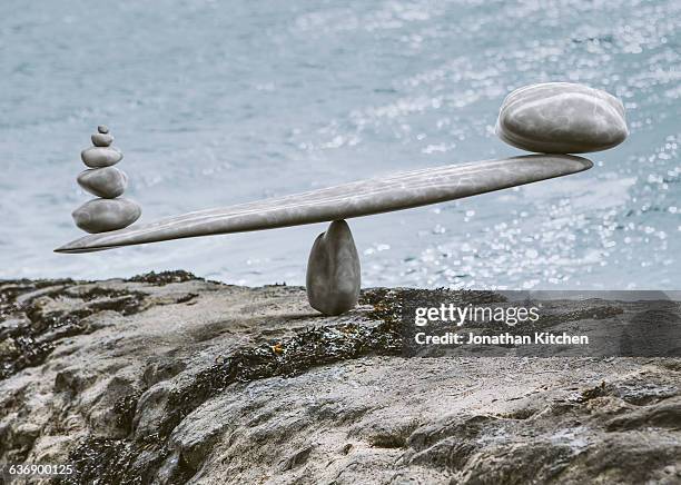 zen-like stone scales on a stone next to sea - balancing act fotografías e imágenes de stock
