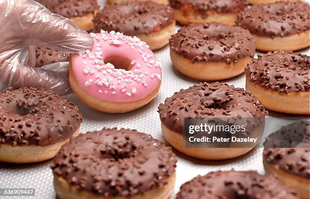 doughnuts chocolate, lifting pink doughnut - rosa handschuh stock-fotos und bilder