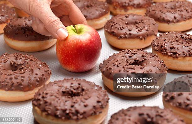 doughnuts chocolate, with hand taking apple - transfettsäure stock-fotos und bilder