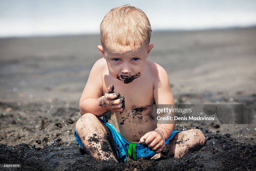 Happy dirty child play with sand on family beach vacation