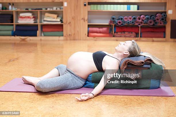 schwangere frau liegt in savasana yoga pose - yoga kissen stock-fotos und bilder