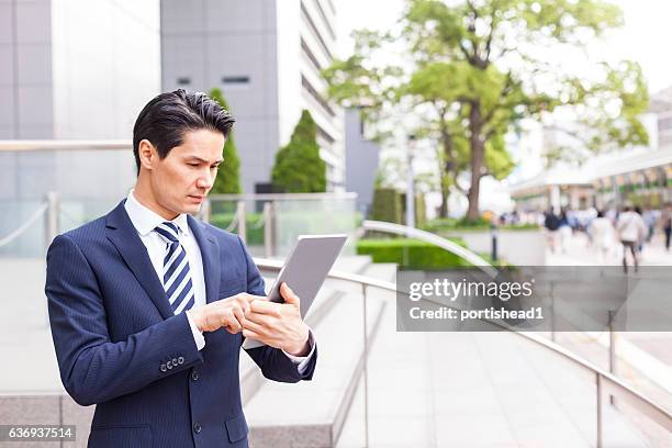 uomo d'affari preoccupato che usa il tablet digitale davanti ai grattacieli - man suit using phone tablet foto e immagini stock