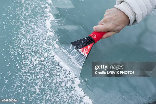 scraping snow and ice from the car windscreen - eau glacée photos et images de collection