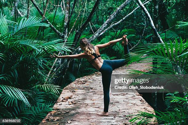 woman doing yoga on tropical forest - yoga retreat stock pictures, royalty-free photos & images