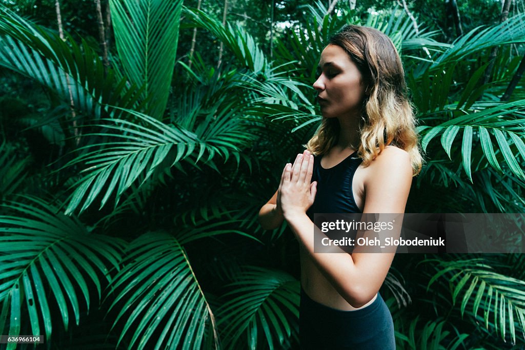 Woman doing yoga in tropical forest