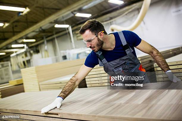 young carpenter carrying wood plank - furniture stockfoto's en -beelden
