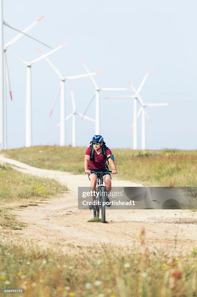 Biker riding in front of wind turbines