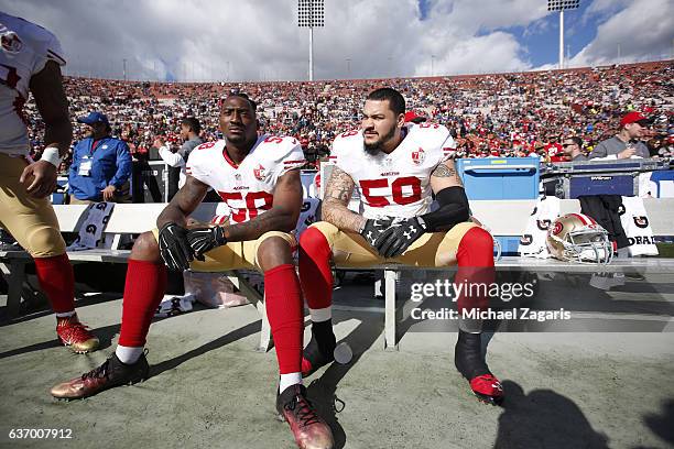 Eli Harold and Aaron Lynch of the San Francisco 49ers sit on the bench prior to the game against the Los Angeles Rams at the Los Angeles Coliseum on...