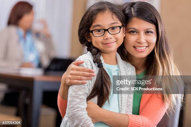 asian mother and daughter wait in hospital waiting room - filipino girl stockfoto's en -beelden