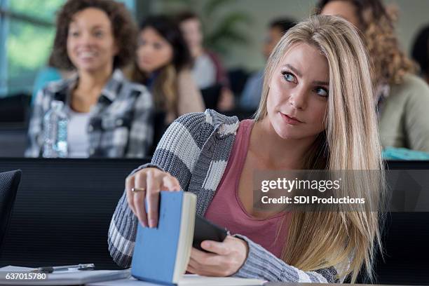 studentessa universitaria nasconde il telefono mentre mando messaggi in classe - golf cheating foto e immagini stock