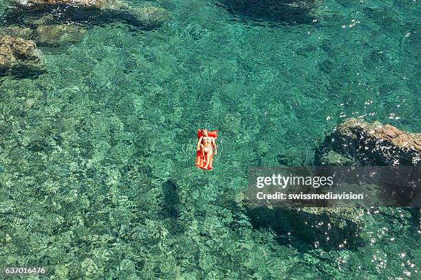 young woman relaxing on floating mattress above sea - pool raft imagens e fotografias de stock