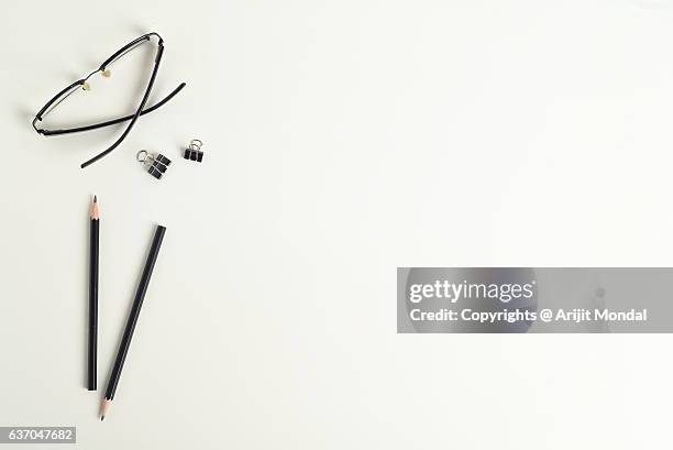directly above shot of eye glass, pencils with blank copy space on white background - reading glasses on table stock pictures, royalty-free photos & images