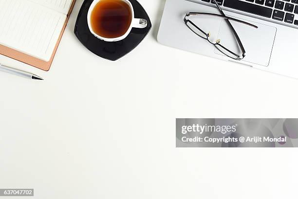 white office desk table with a laptop, notebook, cup of tea and eye glasses on it, top view with copy space. - tea cup overhead view photos et images de collection