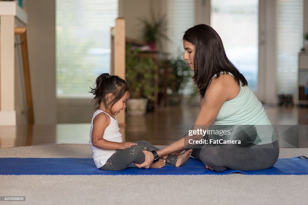 Pregant mãe étnica fazendo yoga com sua menina bebê