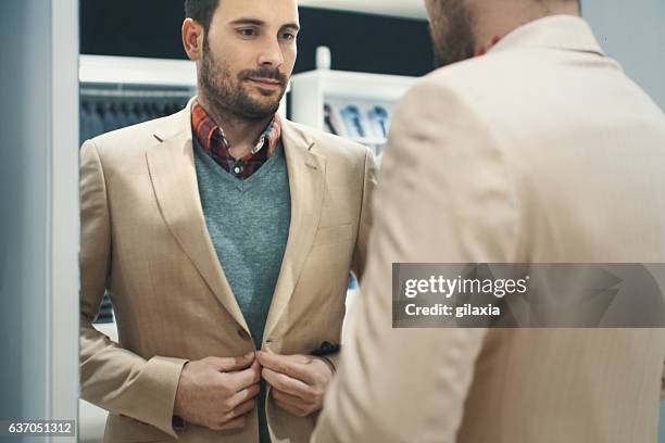 man buying some clothes. - beige jacka bildbanksfoton och bilder