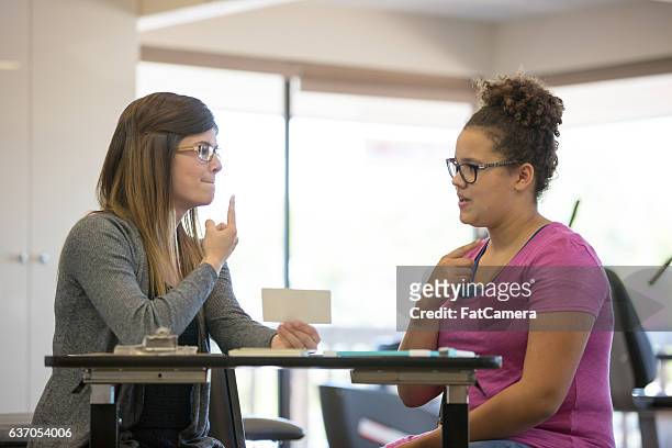 terapeuta del habla femenina que ayuda a un paciente adolescente dentro de una clínica - adultos fotografías e imágenes de stock
