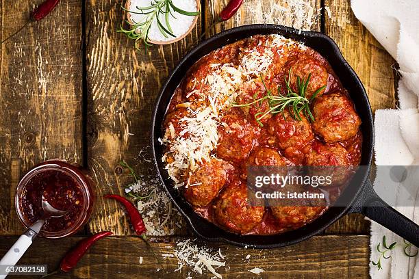 meatballs in sour tomato sauce with grated parmesan cheese on top - gusseisen stock-fotos und bilder