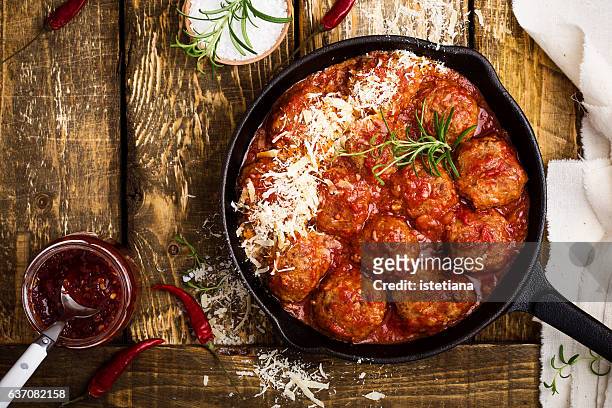 meatballs in sour tomato sauce with grated parmesan cheese on top - gehaktbal stockfoto's en -beelden