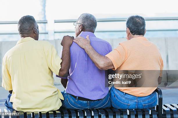 three multi-ethnic senior men sitting on bench - african american man helping elderly bildbanksfoton och bilder