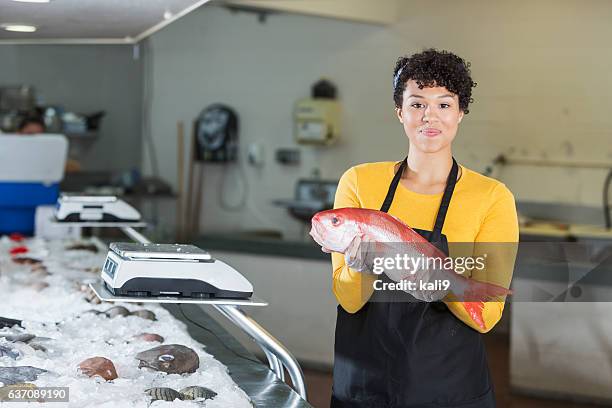 mixed race woman working in fish market - fishmonger stock pictures, royalty-free photos & images