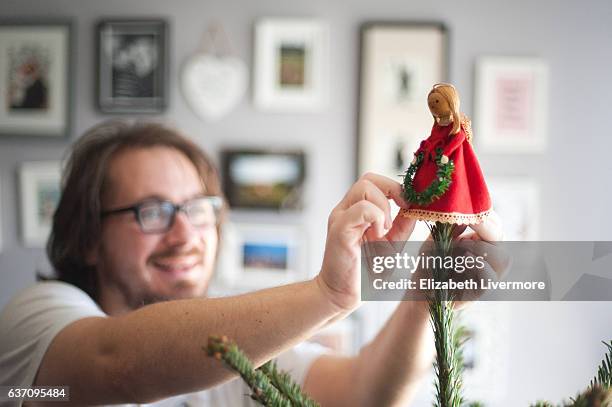 man decorating christmas tree - tree topper stock pictures, royalty-free photos & images