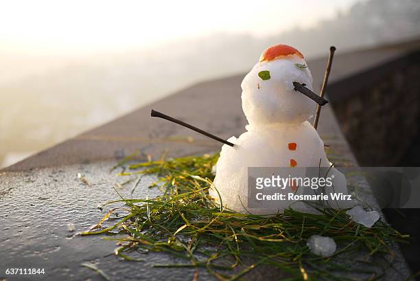 small snowman sitting on wall - melting snowman stock pictures, royalty-free photos & images