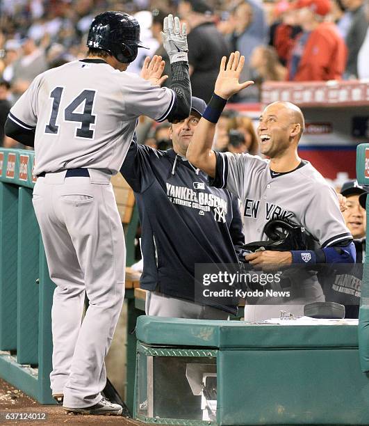 The United States - The New York Yankees' Derek Jeter gives a high-five to teammate Brian Roberts in the dugout after Roberts hit a solo homer in the...