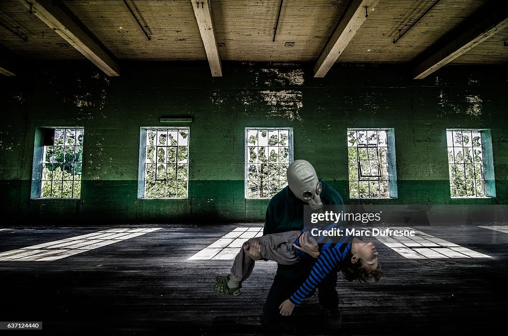 Father with gas mask holding dead son inside abandoned building